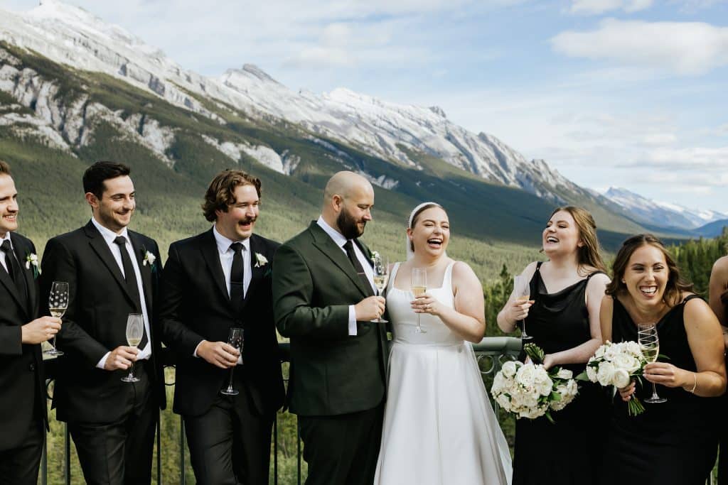 wedding party takes photos on mountain view patio at The Rimrock Resort in Banff