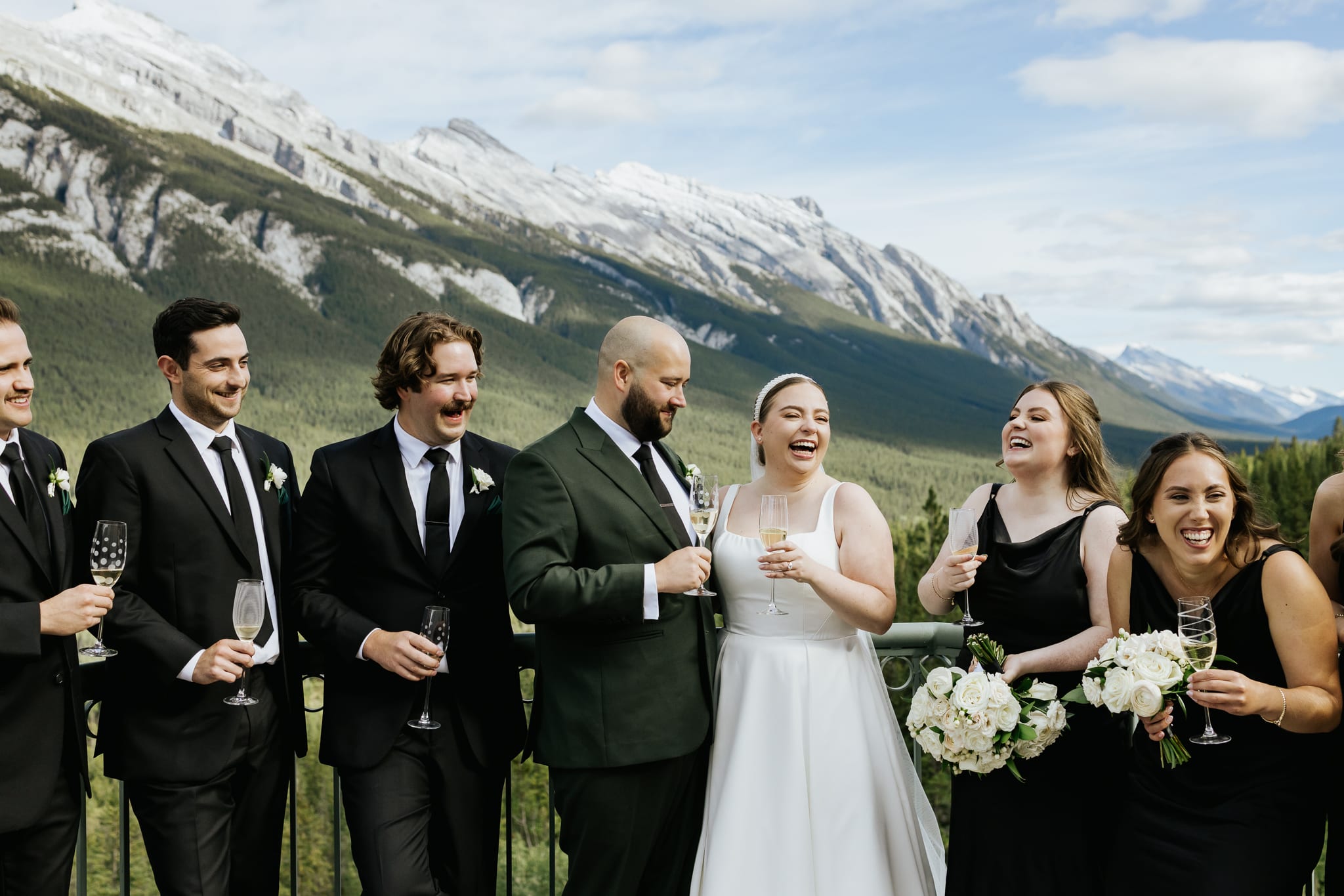 wedding party takes photos on mountain view patio at The Rimrock Resort in Banff