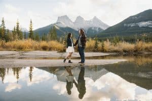 couple takes engagement photos in Canmore with view of Three Sisters Mountain